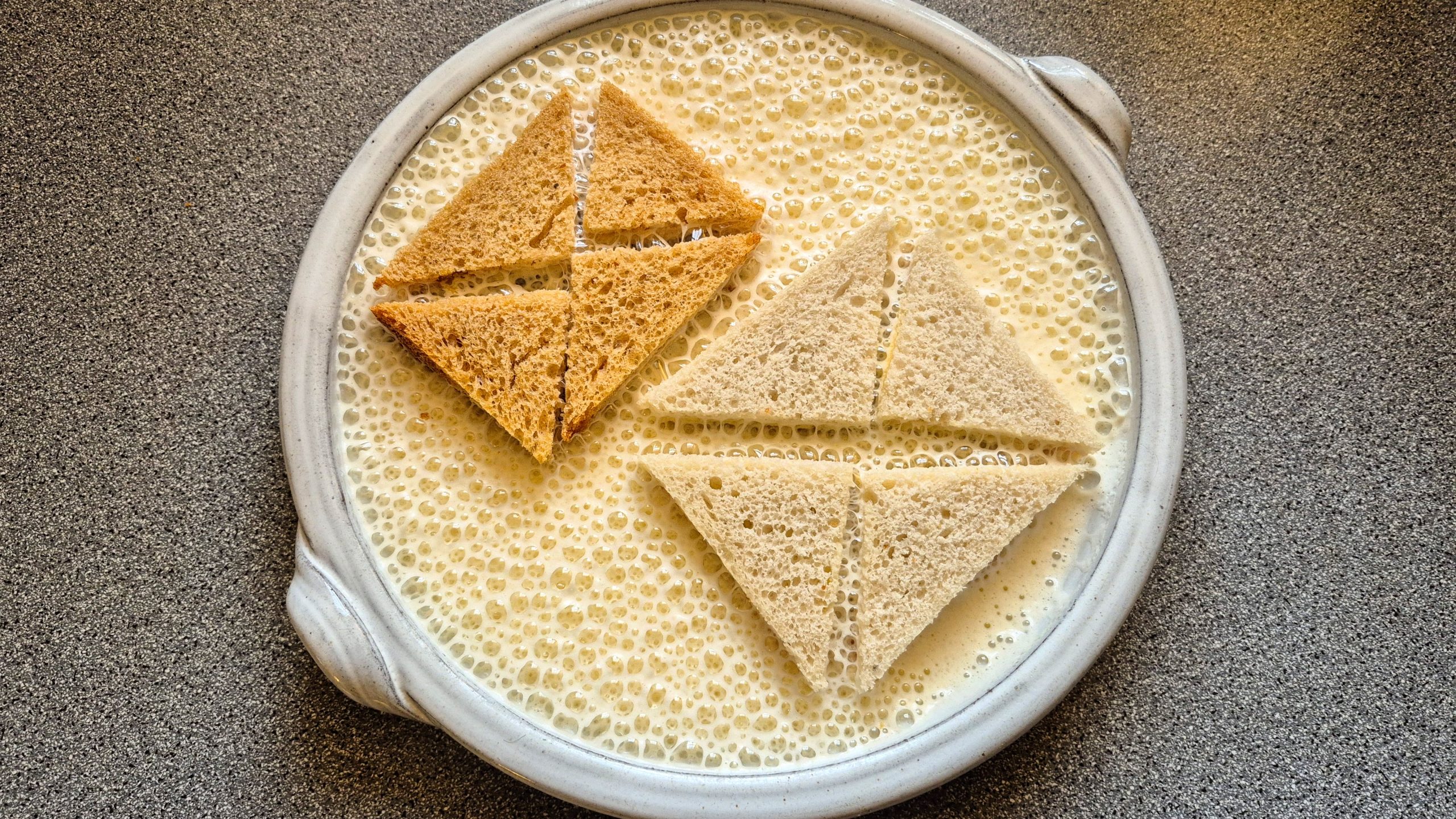 The sandwiches lying in the (surprisingly foamy) egg and milk mixture