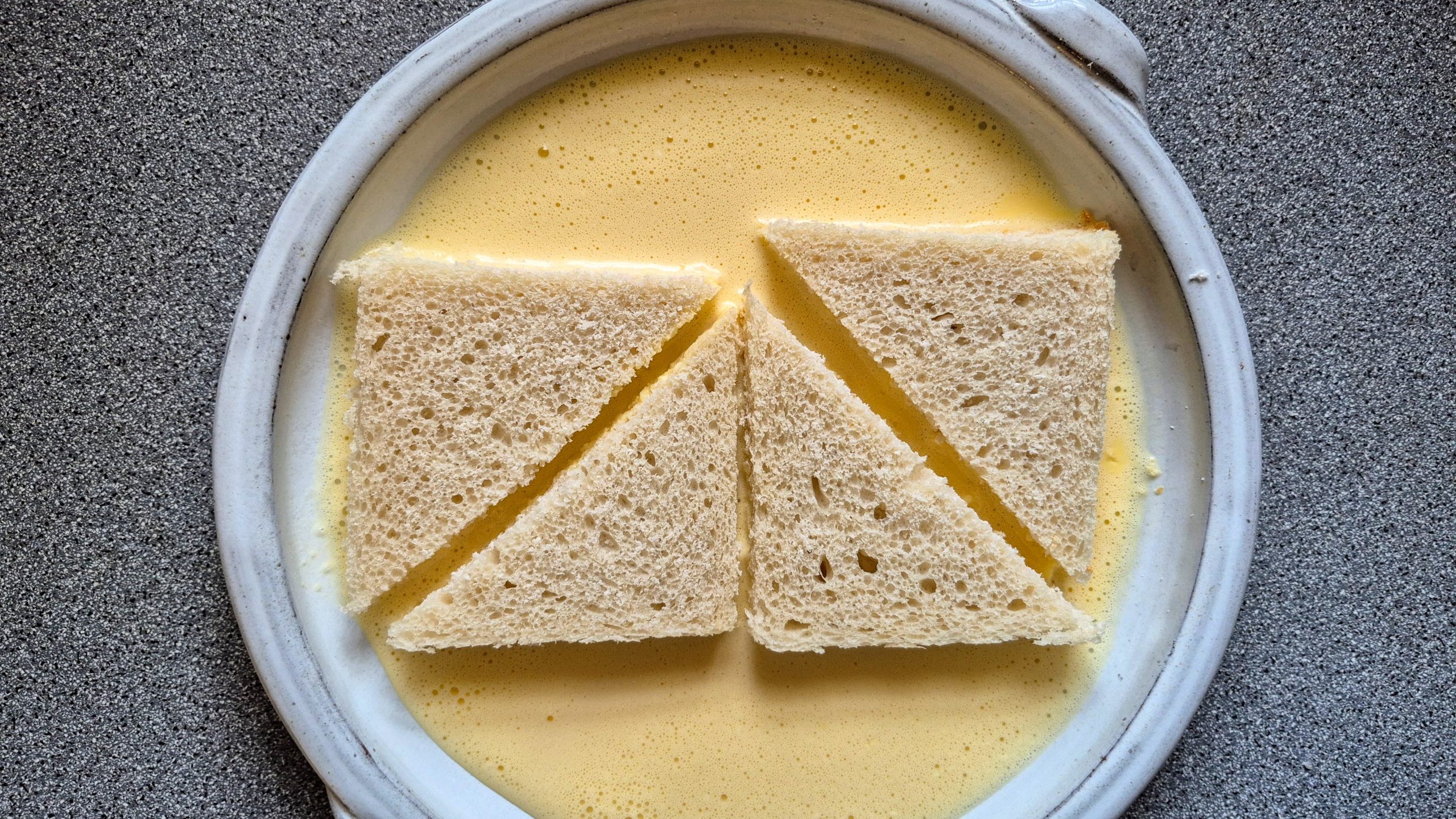 Bread slices lying in the egg-and-cream mixture